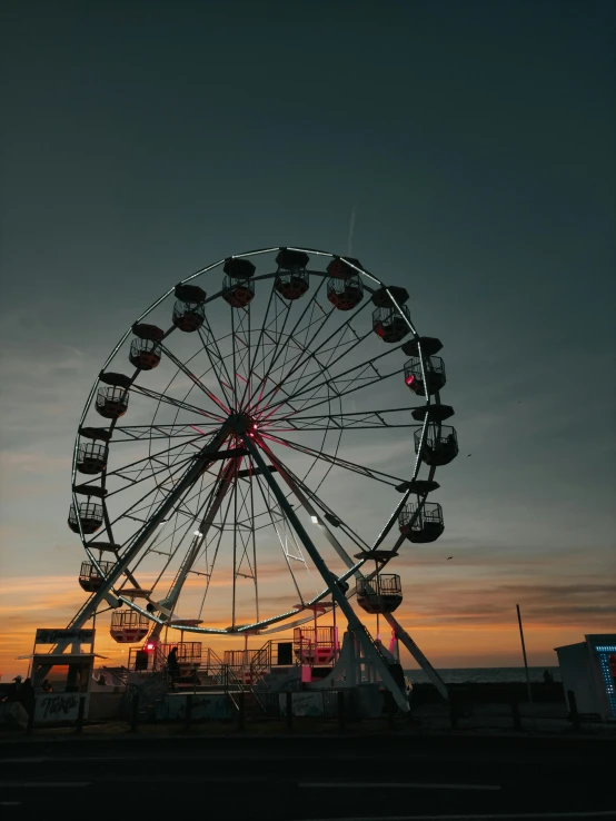 a ferris wheel sitting next to a street at sunset