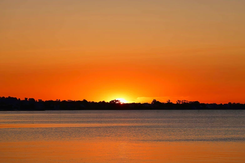 the sunsets over a body of water with small boats