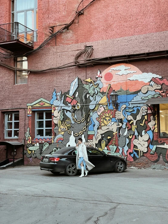 the car is sitting outside the building with graffiti