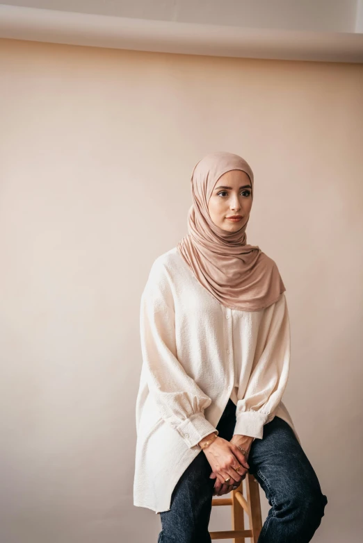 a woman in white sitting on a stool and posing for a po