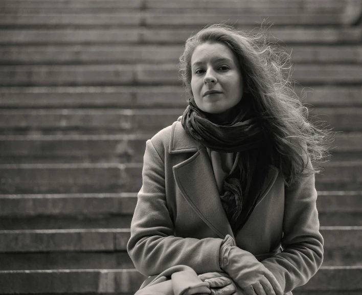 the woman with long hair is standing near stairs