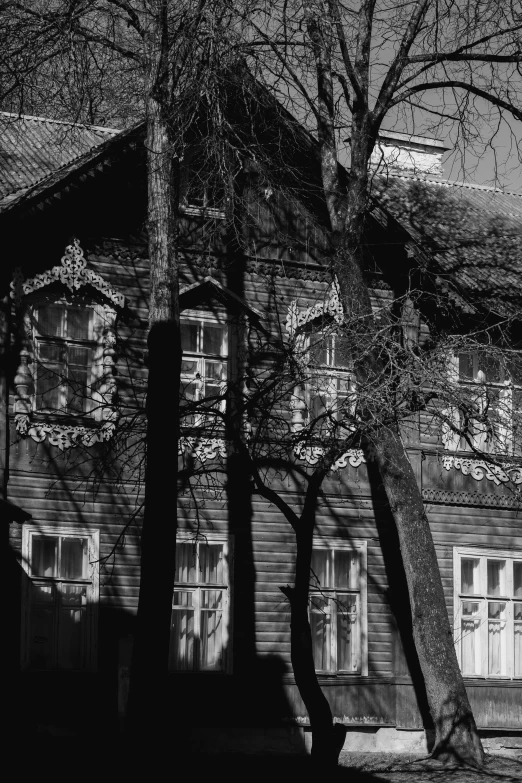 black and white image of a house that has trees in front