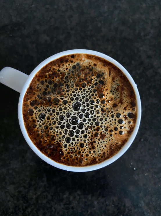 there is a cappuccino on a dark table