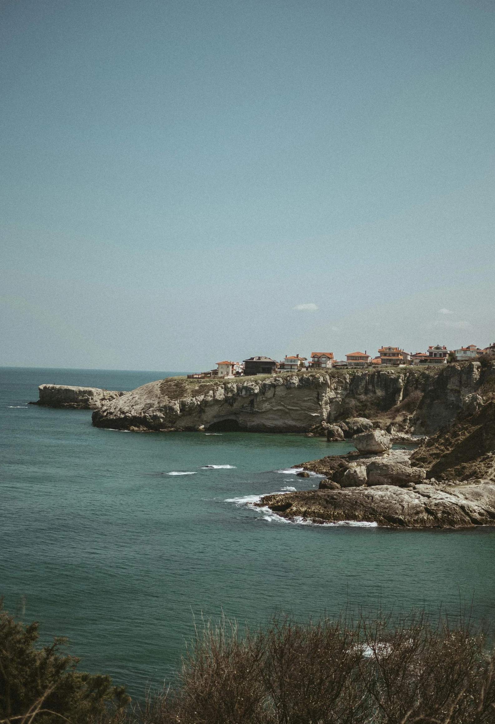 the rocky coast has some rocks and buildings by the water