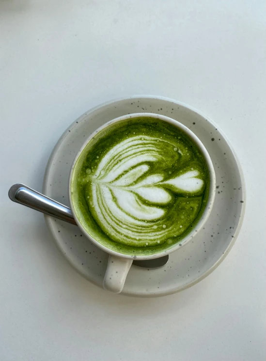 a cup of green coffee with a leaf painted on the inside