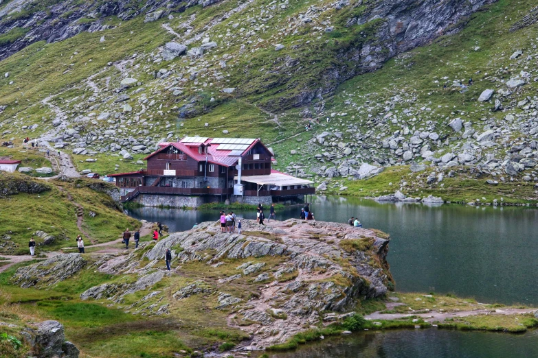 a group of people standing next to a lake and building