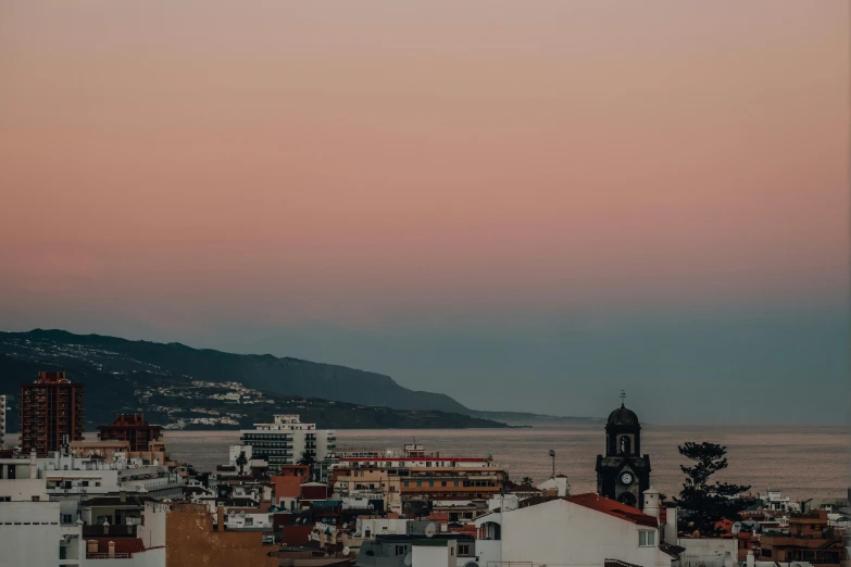 the city with mountains in the background is seen during sunset