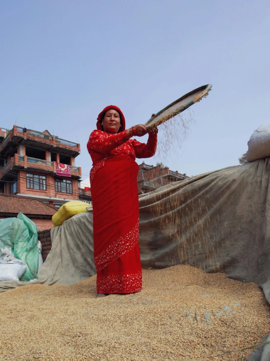 a woman in red stands by a field with sand and a plastic sheet