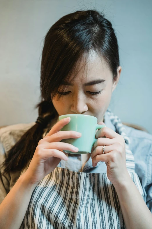 a woman holds a glass of tea as she sips it