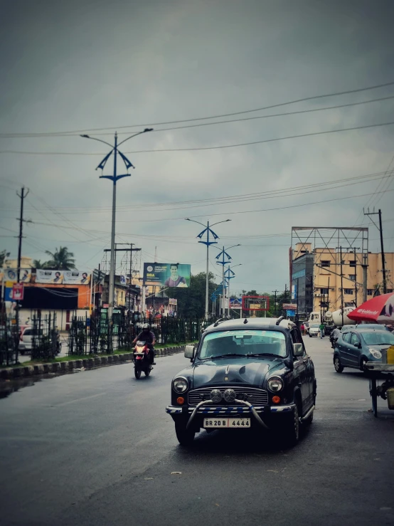 a black car and a motorcycle riding down a road