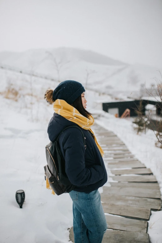 a person wearing a jacket and jeans stands in the snow