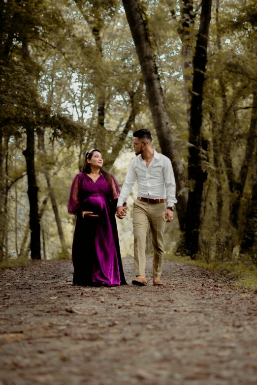 an old fashioned couple is walking down a trail with tall trees