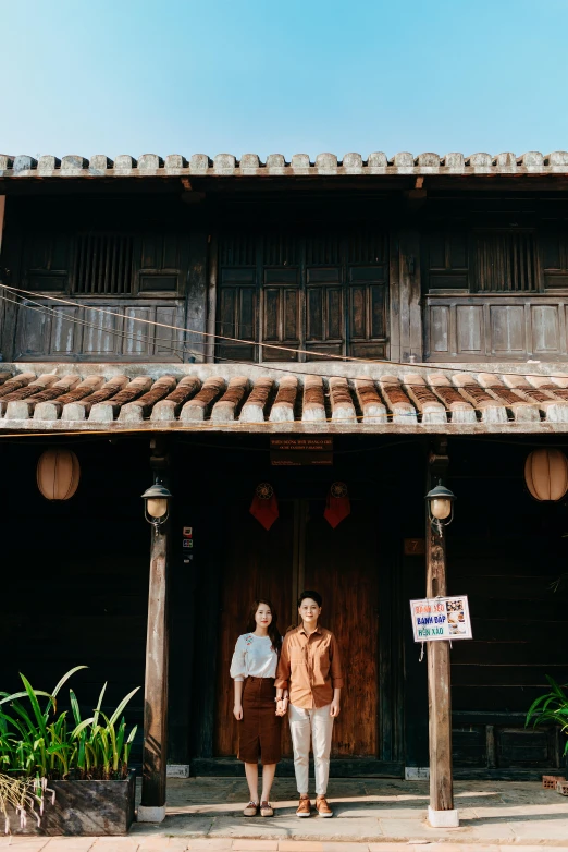 two people standing outside an old building in front of a banner