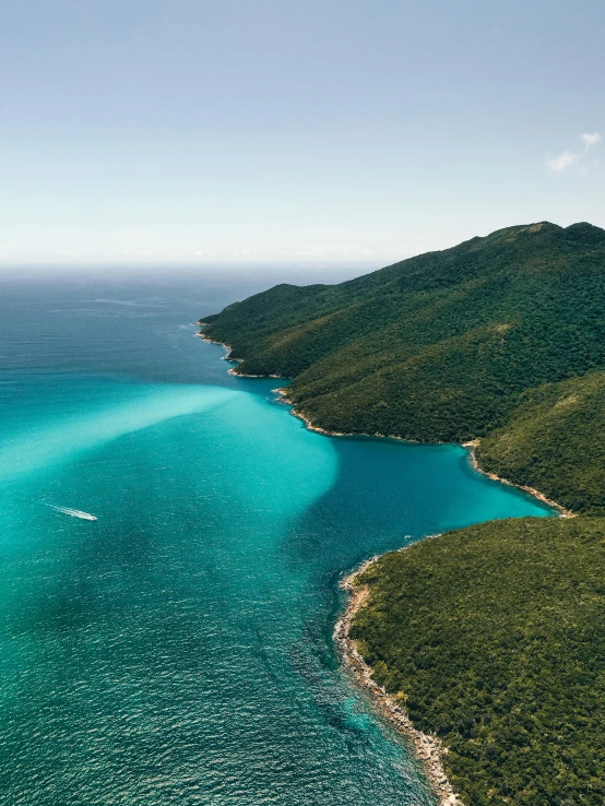 a large body of water next to a lush green mountain side