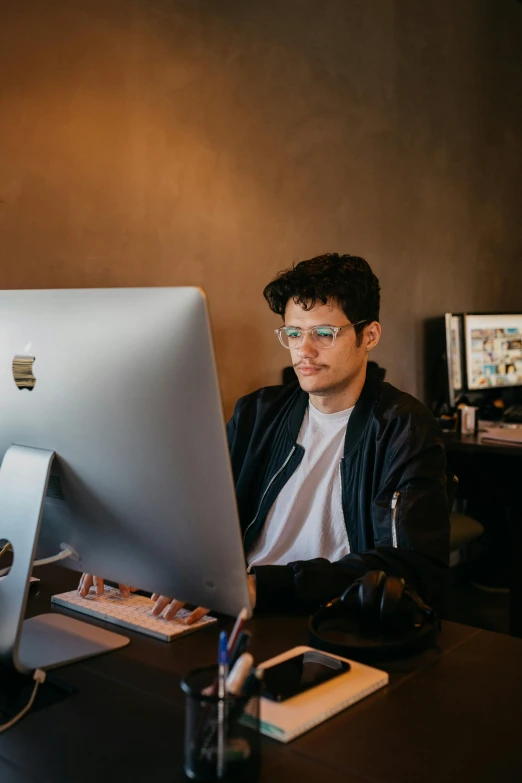 man in glasses typing on an apple computer