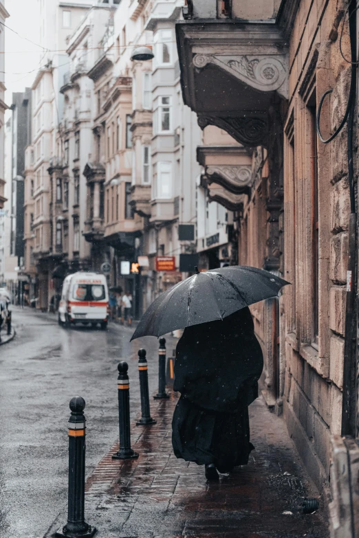 a person kneeling down in the rain holding an umbrella