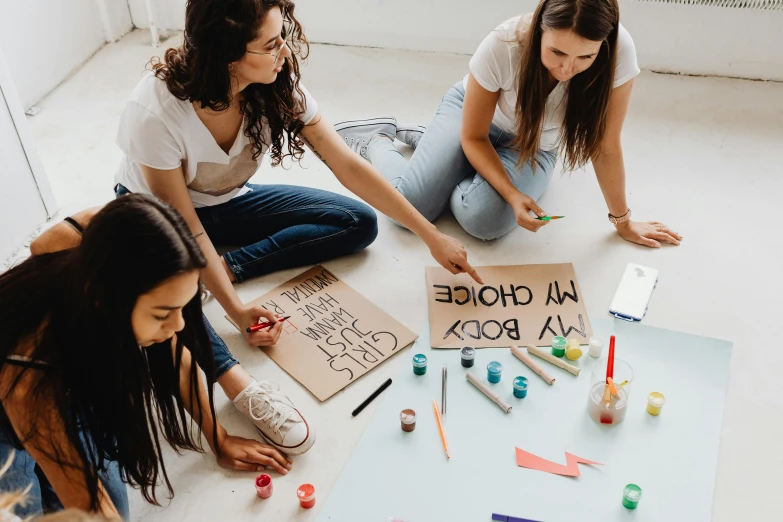 two women sitting on the floor drawing and coloring