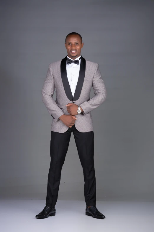 a man standing and smiling in a suit and bow tie