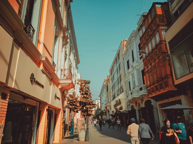 people walk down a street between large building