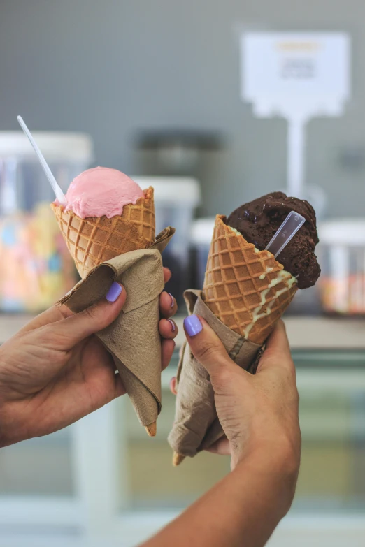 two cones are being held with forks to eat them