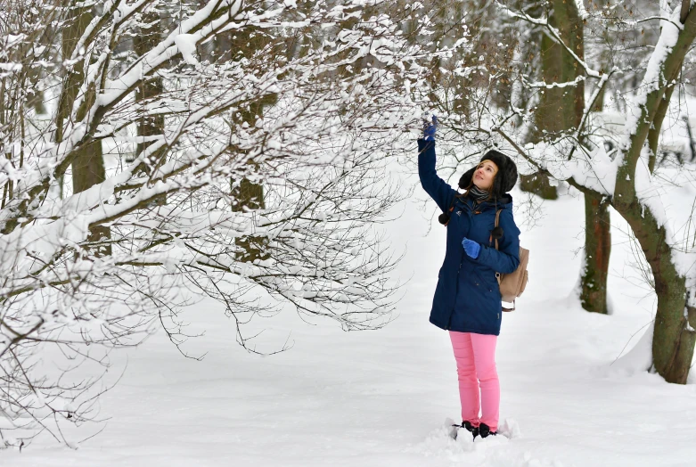 a girl stands in the snow with her arms up