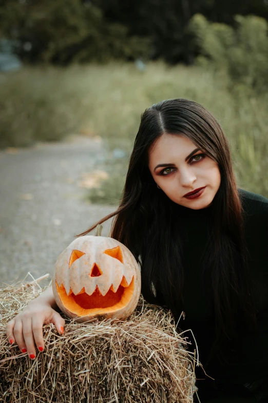 woman sitting in the grass with a jack - o'- lanterns