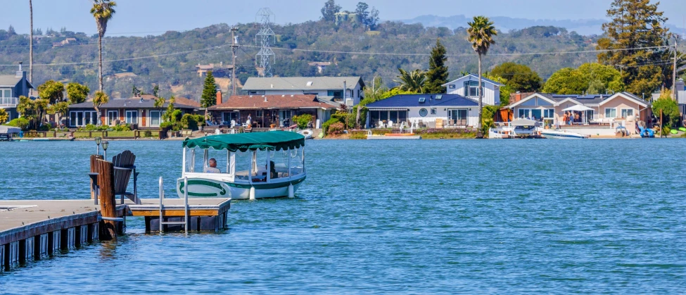 a boat docked next to some houses on the side of a lake