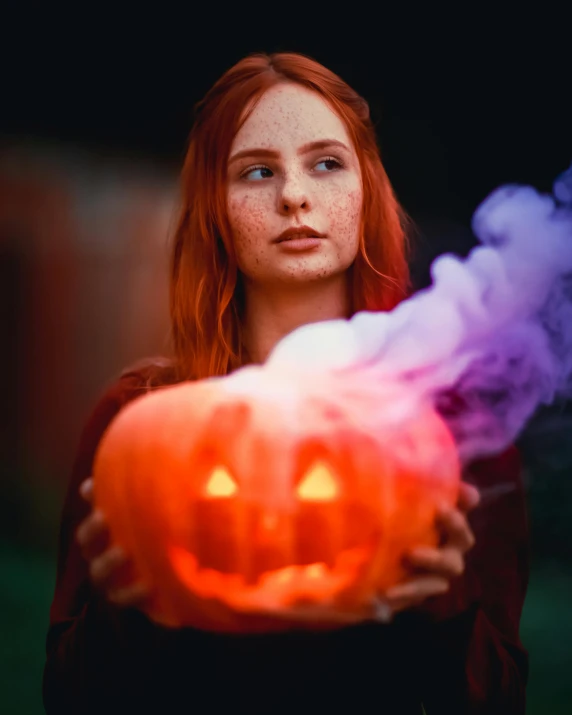 a girl holds a carved jack o lantern