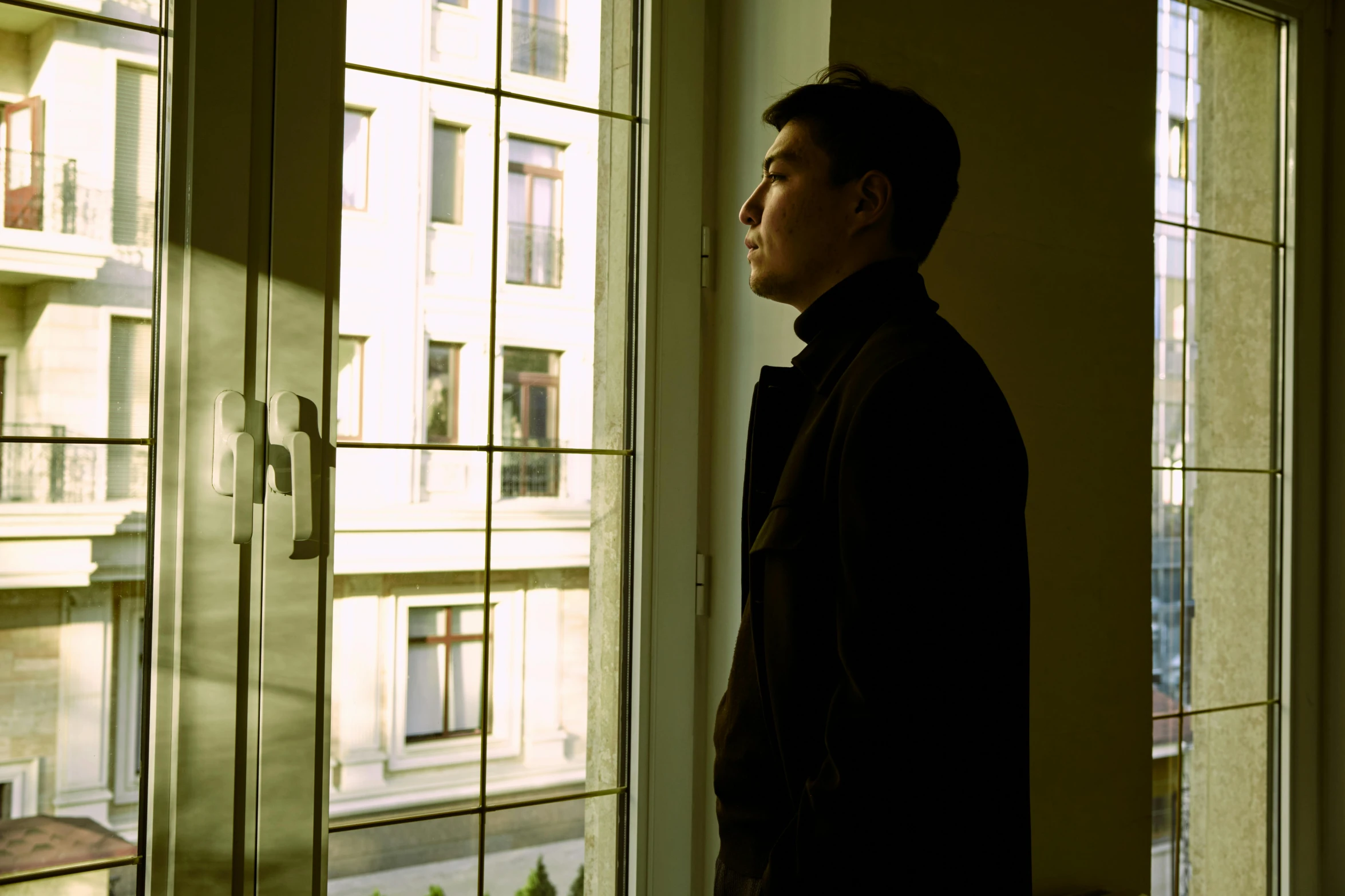 a man in an empty apartment looking out the window