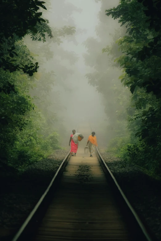 some people are crossing the tracks near a tree line