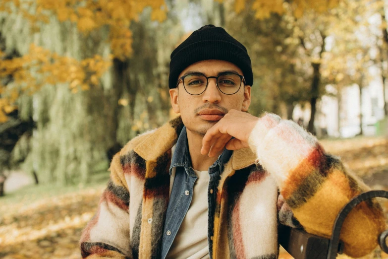 a man wearing glasses sits on a park bench