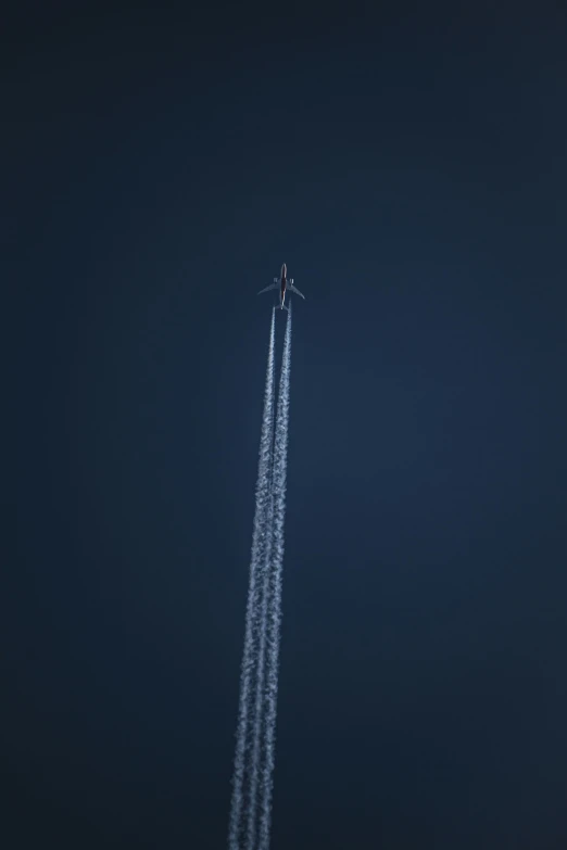 a jet flying very high into the sky leaving its trailing trail