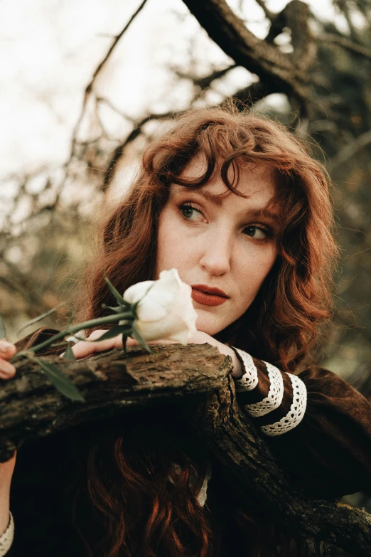 a young woman is holding onto an old nch with white flowers