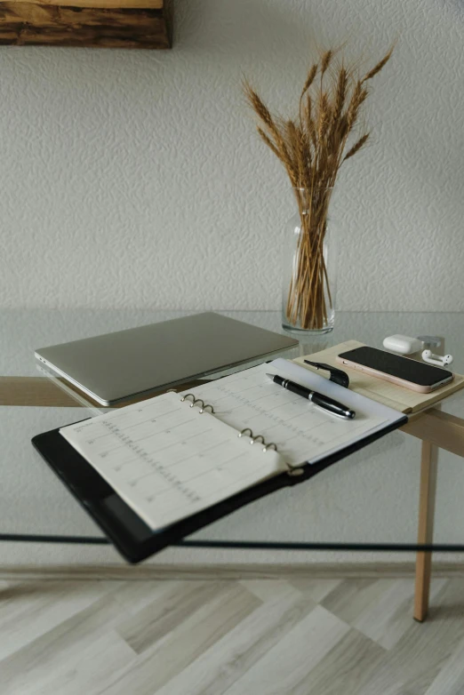 an open planner, pen and phone on a glass table