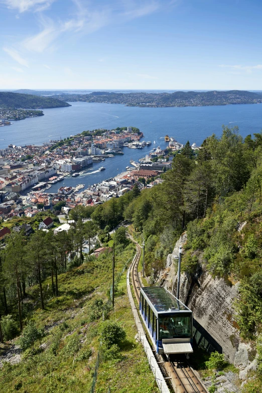 train traveling along tracks over green hillside with a view of the ocean