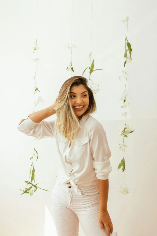 a beautiful young woman standing in front of a white wall