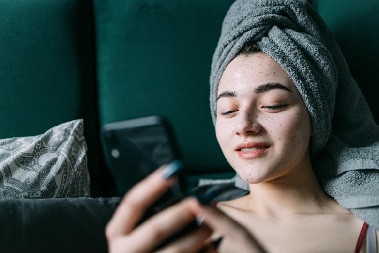 a woman with towel on her head is looking at her cell phone