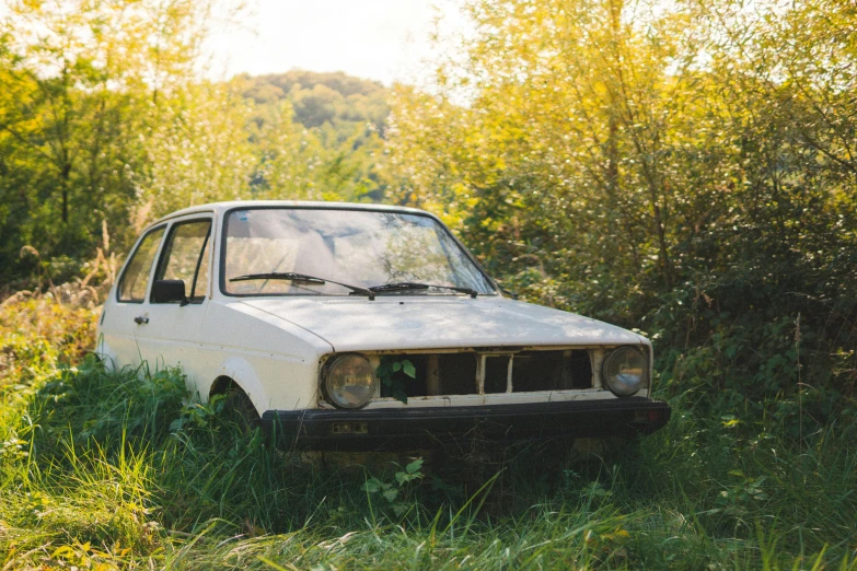 a white car is in the weeds with some trees