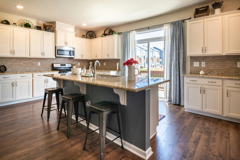 a kitchen island and stools are in this large open space