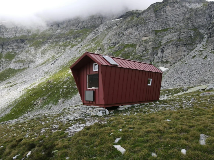 a red small cabin sitting on the side of a mountain