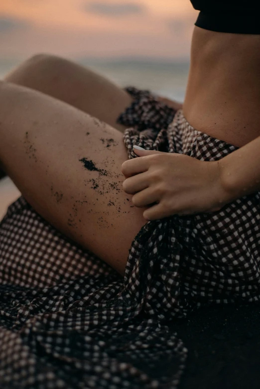 a lady is laying on a rock with her feet in sand