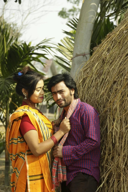 a man and woman in orange sari with tree