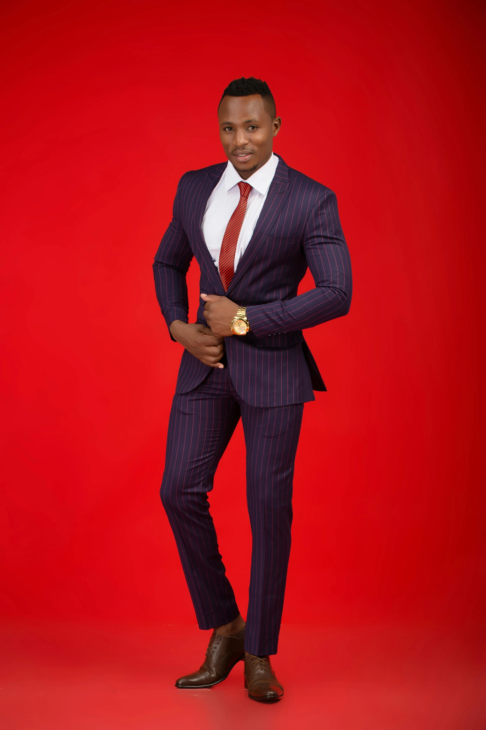 young man in suit smiling for camera against a red background