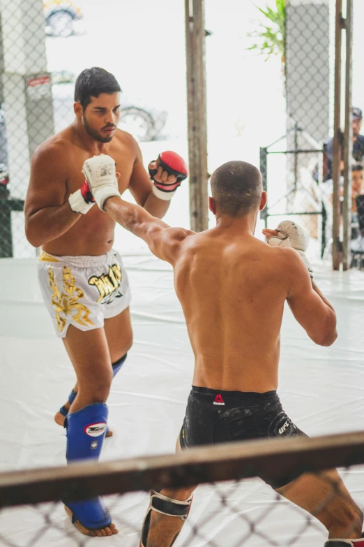 two men in boxers stand next to each other, one has boxing gloves on his hand