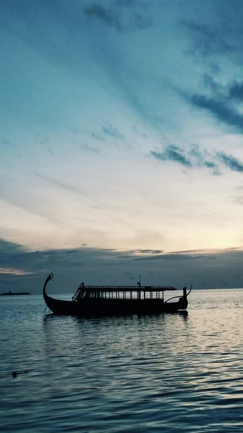 a long boat on the ocean in front of a cloudy sky