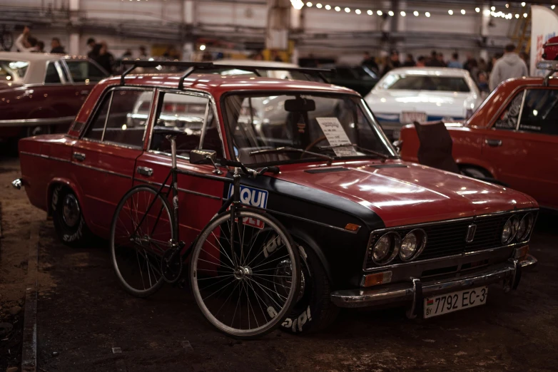 a vintage red car with a bicycle attached to the front