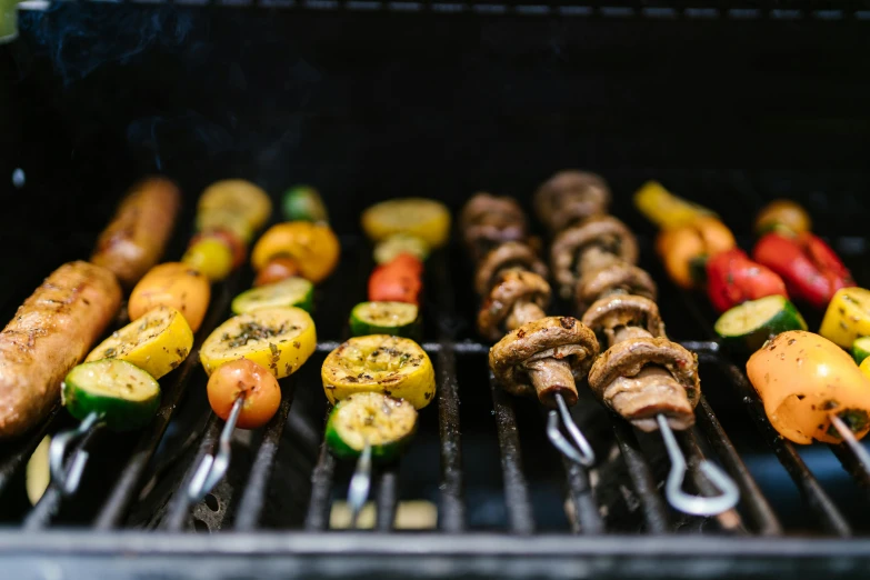 many skewers of vegetables cooking on a grill