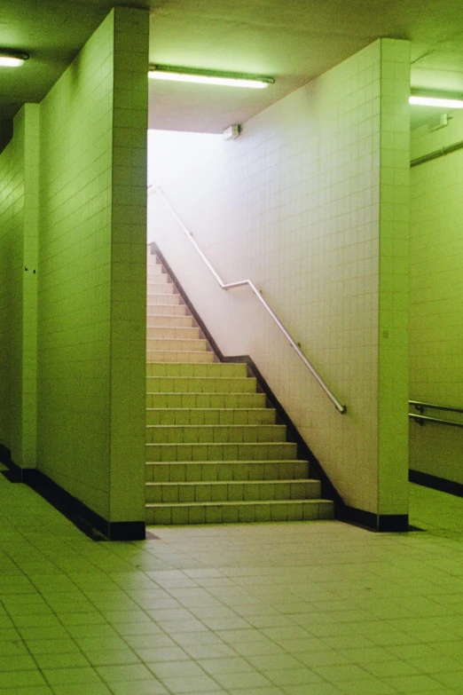 a set of stairs leads down into a green subway station