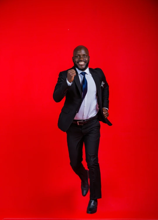 a man in a black suit running through a red background