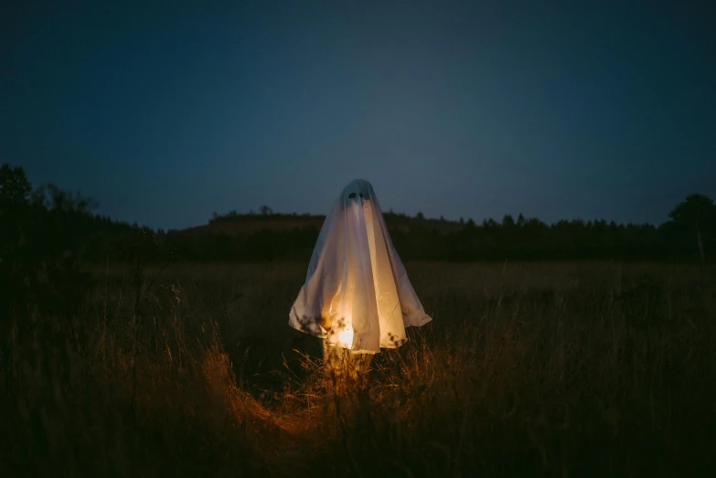 a tent set up in a field illuminated with lanterns at night